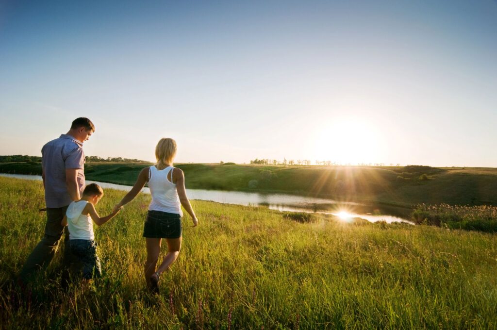 Family walking in a field at sunset
