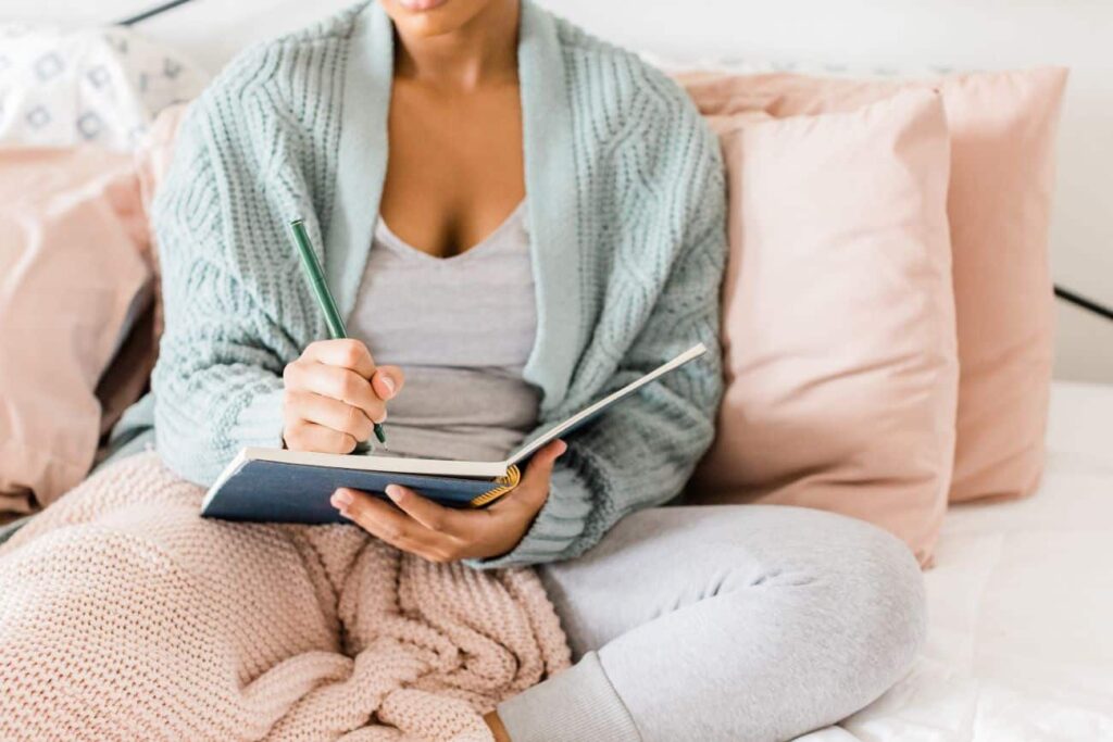 Different types of journals to keep -  Woman writing in journal while in bed