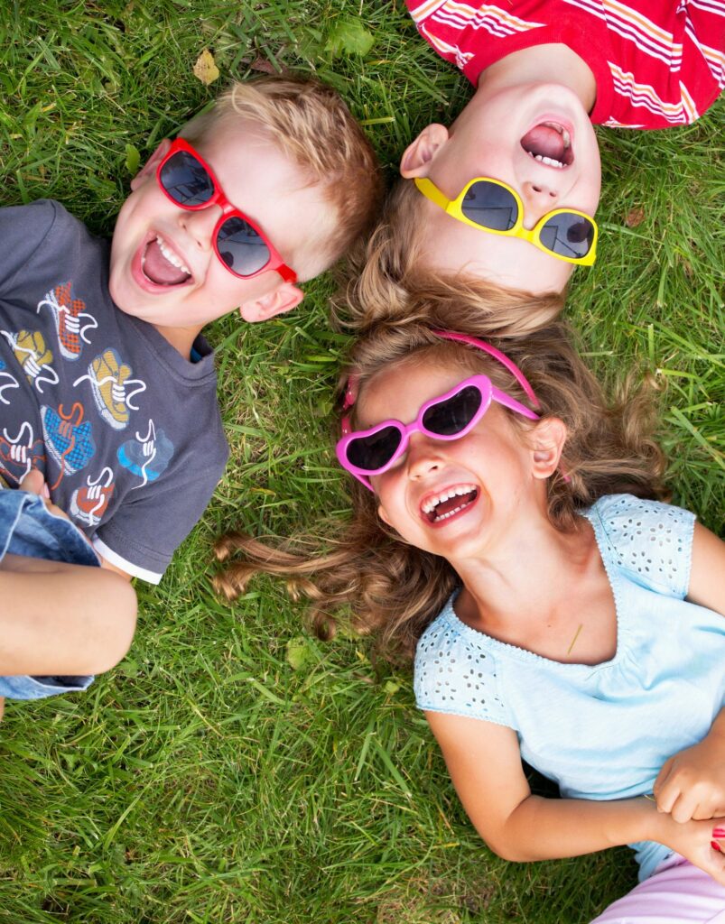 Kids laughing with sunglasses on in their backyard